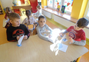 Dzieci układają przy stoliku obrazki z części.